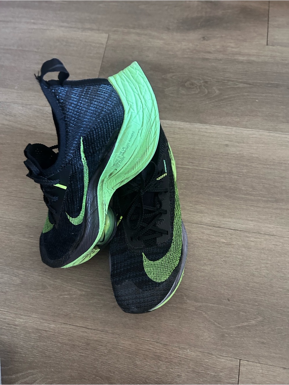 Nike ZoomX performance running shoes in black with neon green accents.